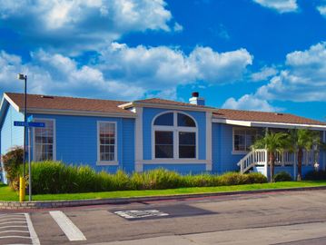 Blue house on corner with palm trees and bright sky.