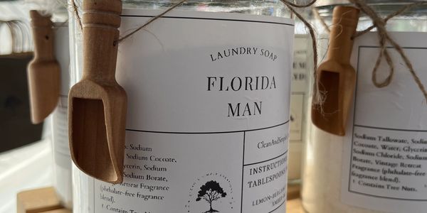 Jar of laundry soap labeled 'Florida Man' with a small wooden scoop attached.