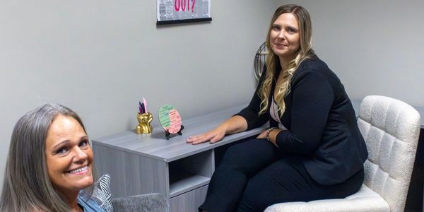 Two women sitting in a modern office smiling.