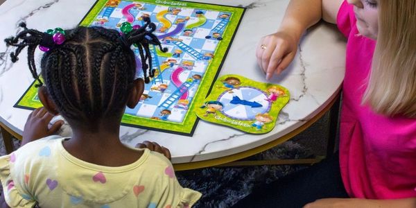 Two children playing a board game on a table.