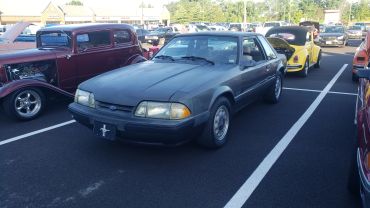 A gray vintage Mustang parked among other classic cars.