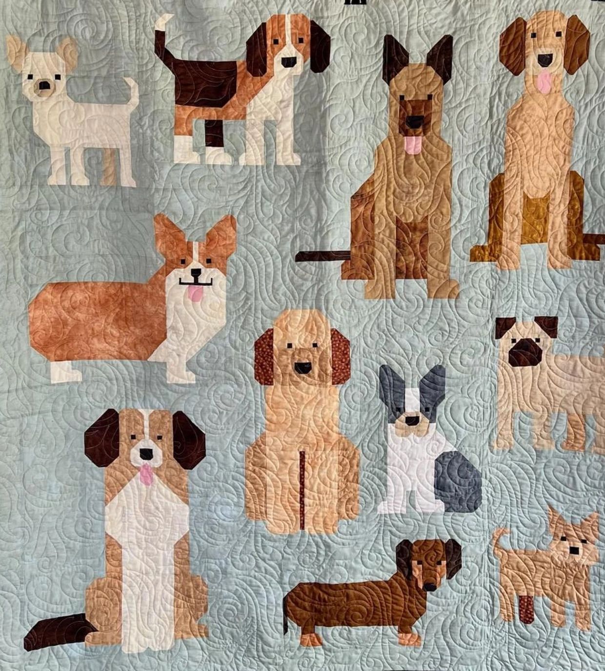 Quilt with geometric dog patterns on a light blue background.