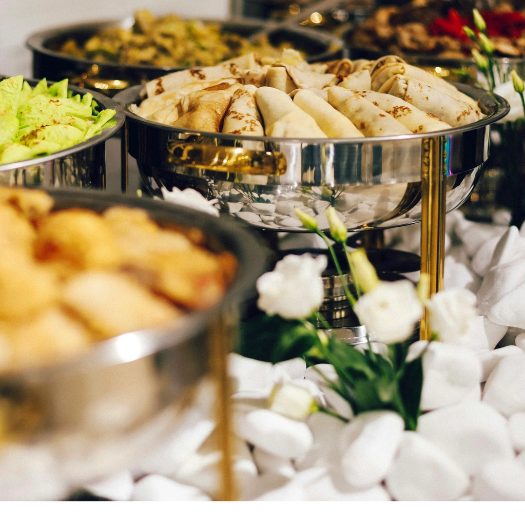 A buffet table with various dishes and white flowers as decor.