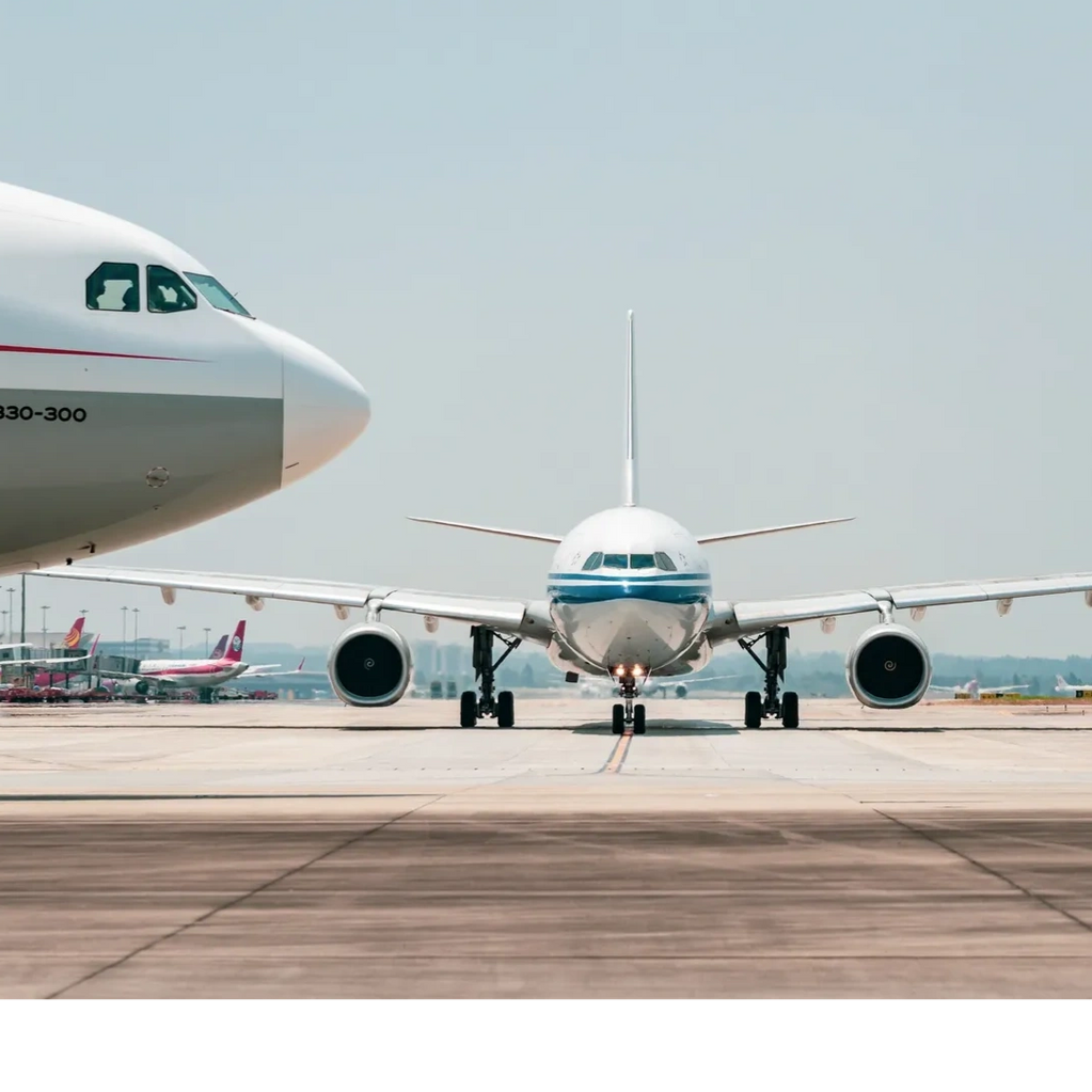 Two airplanes on the runway at an airport under clear skies.