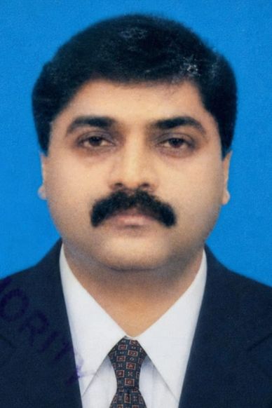 Formal ID photo of a man in a suit and tie with a blue background.