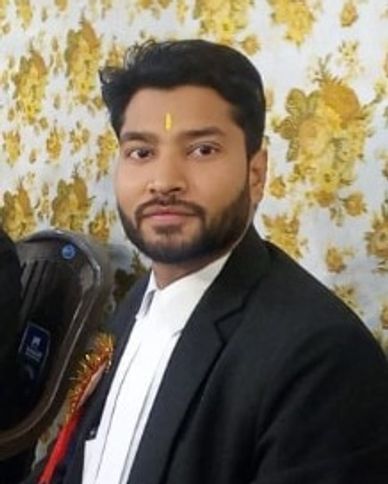 Young man in formal attire with a traditional tilak on his forehead.