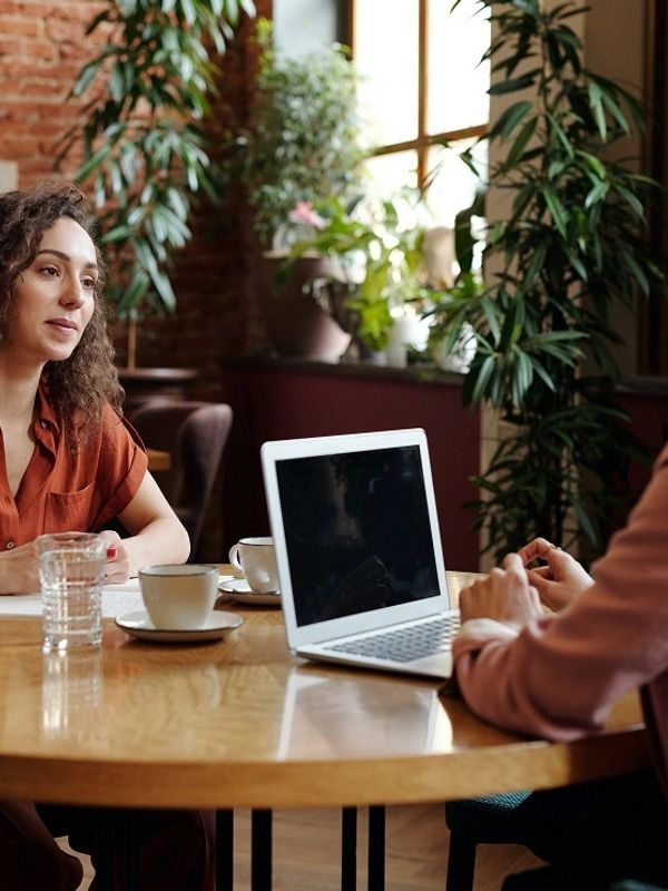 Two people having a meeting with a laptop and coffee cups.