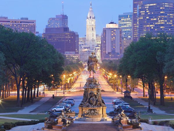 Cityscape of Philadelphia with a prominent statue in the foreground.