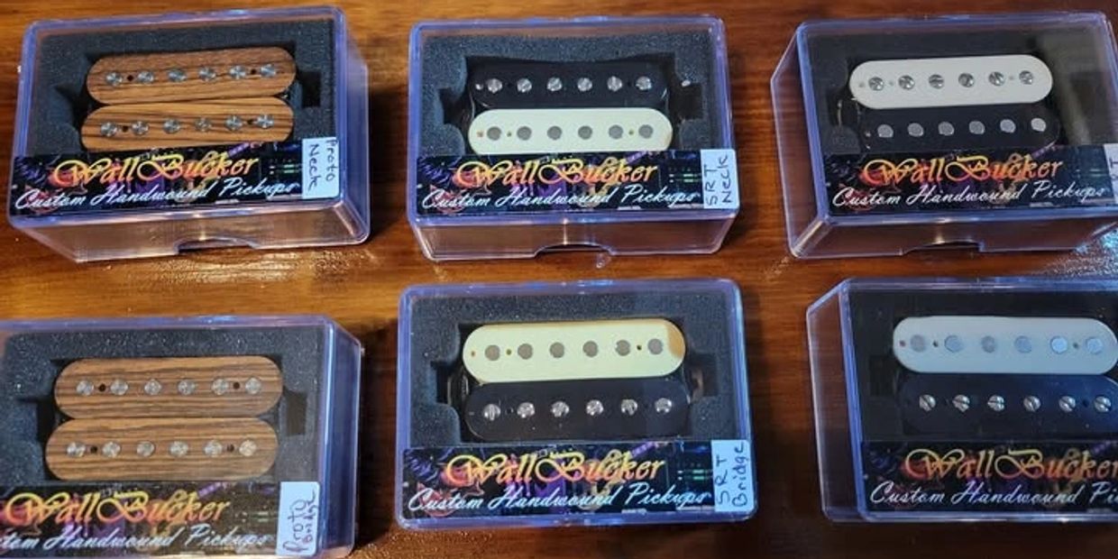 Six sets of custom handwound guitar pickups in clear plastic boxes.