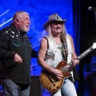 Two musicians performing on stage with guitar and vocals.