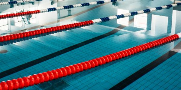 Empty indoor swimming pool lanes with red and blue lane dividers.
