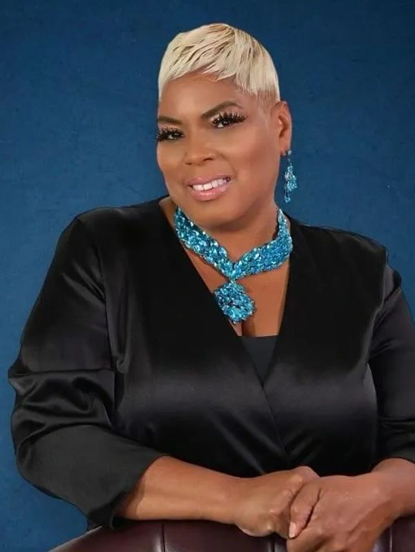 A woman wearing black suit and sitting on the chair with looking ahead