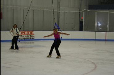 wide view of figure skaters using jump harnesses