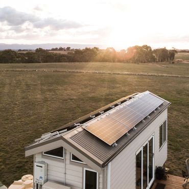 Low aerial of the Tiny House showing solar panels on the roof, looking across to the Grampians.