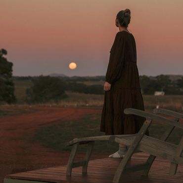 A guest looks out at a full moon from the deck at the tiny house.