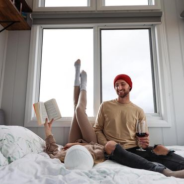 Guests enjoying the space in the Tiny House, reading and drinking a glass of Black & Ginger Wine.
