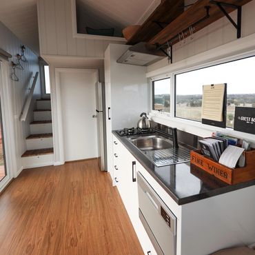 Interior of the Tiny House, shows the kitchenette and stairs to the reading loft.