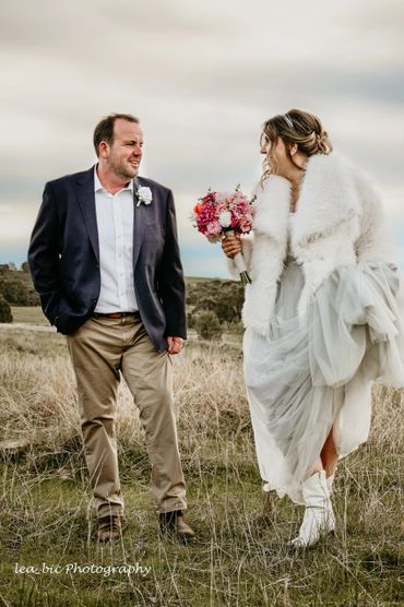 Bride and groom share a joyful moment outdoors on their wedding day.