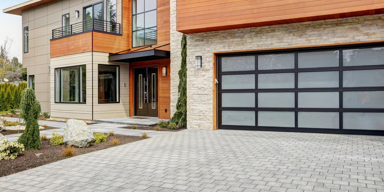 Paver Driveway Installation with grey pavers and a house in the background