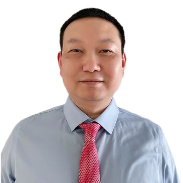 Man in light blue shirt with pink tie smiling against white background.