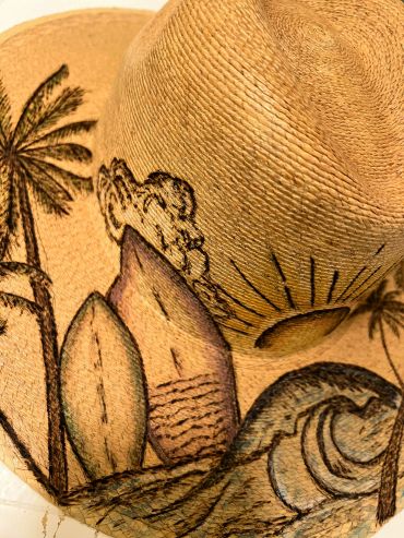 Close-up of a woven straw hat with tropical-themed drawings.