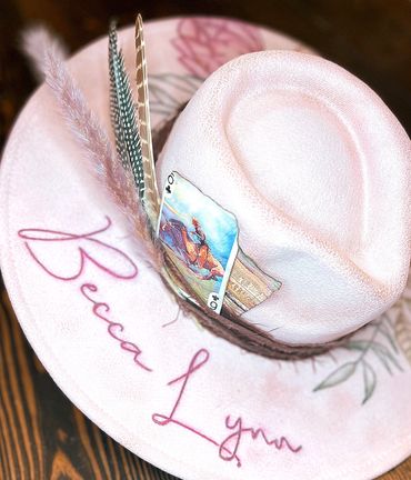 Decorative pink hat with feathers and a playing card.