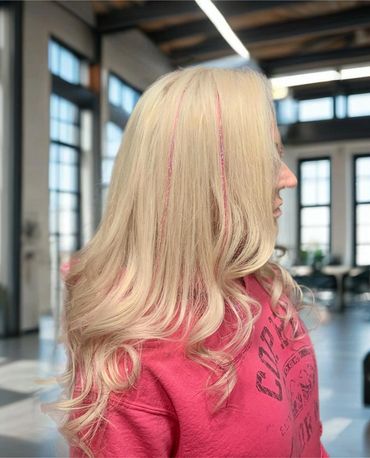 Blonde hair with pink glitter highlights styled in loose curls.