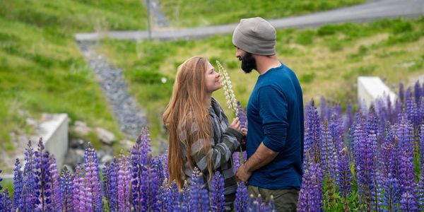 Couple sharing a tender moment in a field of purple flowers.