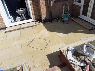 Newly installed beige patio tiles with construction tools around.