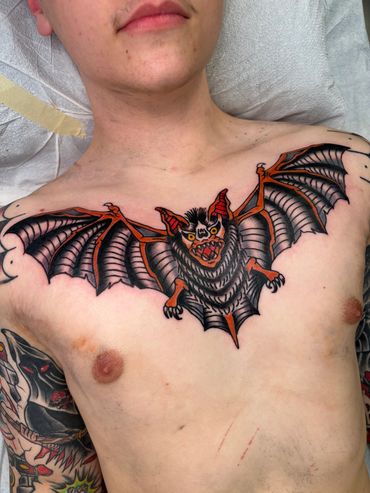 Chest tattoo of a colorful bat with spread wings.