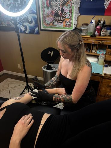 Tattoo artist working on a client's arm in a tattoo studio.