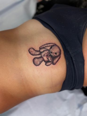 Tattoo of an angry bunny holding a knife on skin.