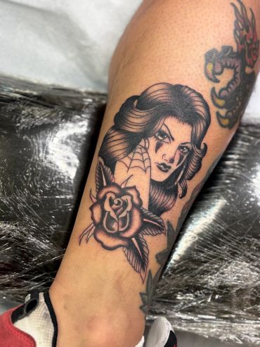 Tattoo of a woman with a rose and scorpion claw.
