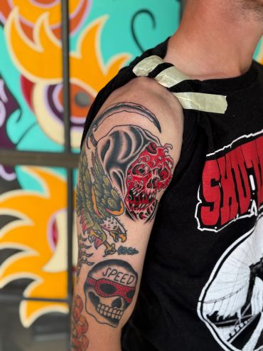 Tattoo sleeve featuring skulls and a colorful background.