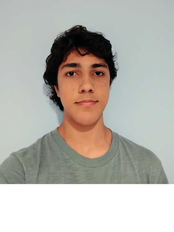 Young man with curly dark hair and green shirt against a plain wall.
