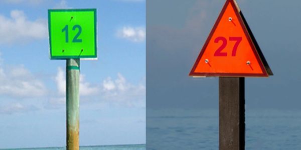 Green square sign with 12 and red triangle sign with 27 on poles.