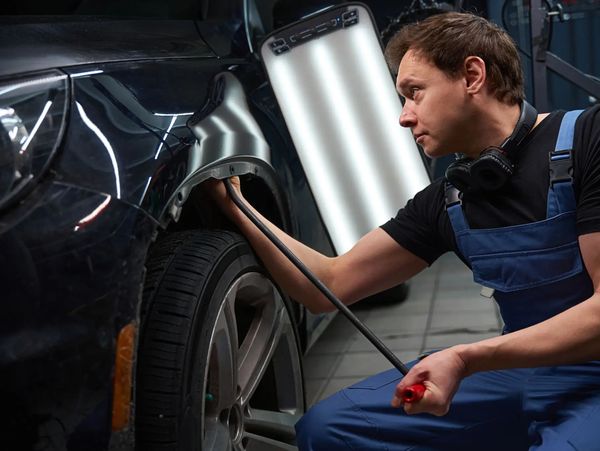 Technician repairing car door dent
