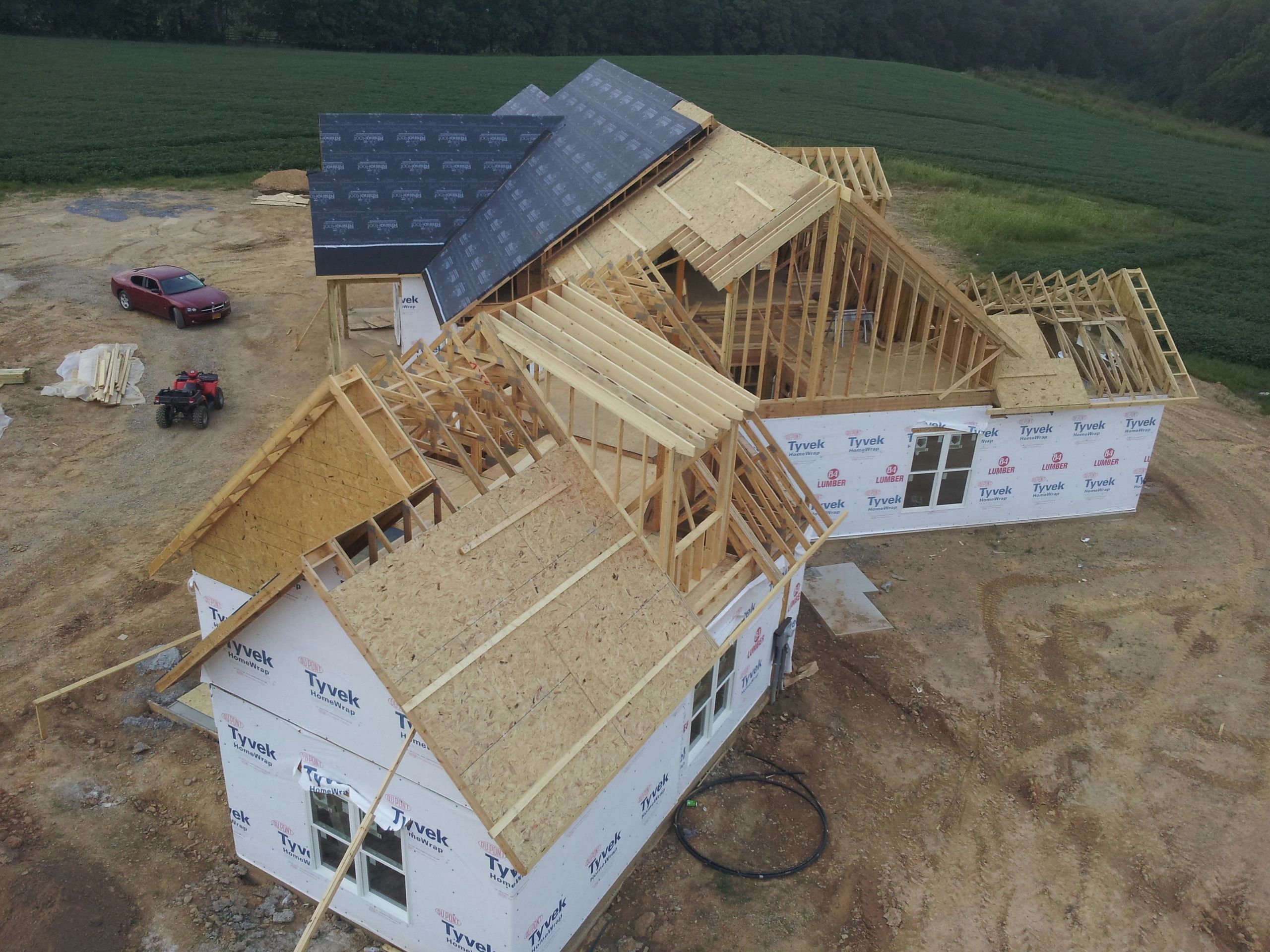 A large house under construction surrounded by fields and dirt.