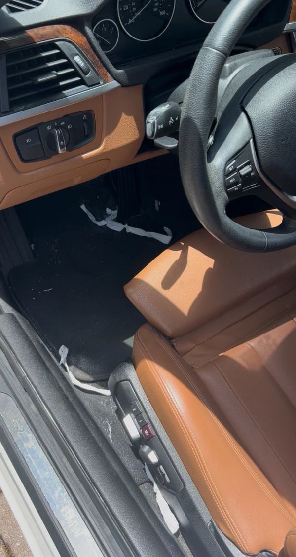 Interior of a car showing the driver's seat and controls with brown leather upholstery.