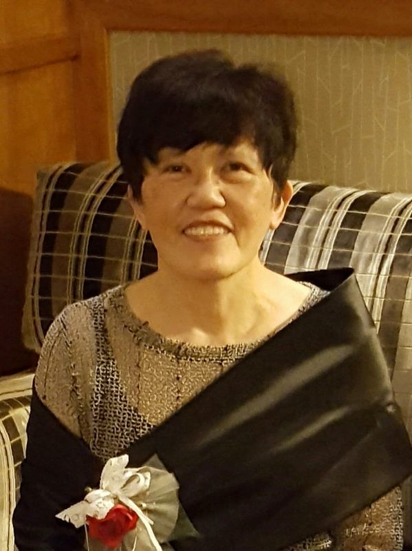Smiling woman sitting with a wrapped flower.