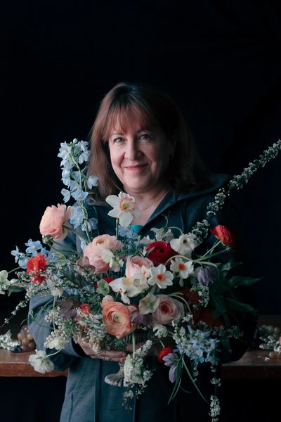 Floral Designer holding lush Dutch master inspired flower arrangement roses, tulips, narcissus