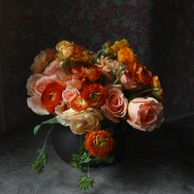 orange and peach, roses and ranunculus in a low centerpiece with greenery