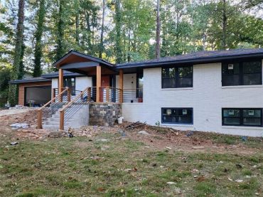 Modern house under construction with white brick exterior and wooden accents.