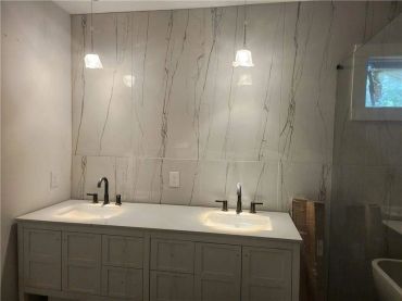 Modern bathroom with dual sinks and marble wall tiles.