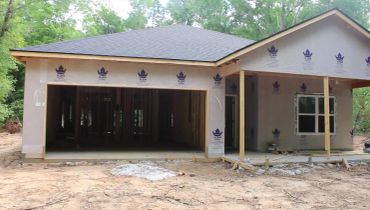 A house under construction with exposed framing and partially covered exterior.