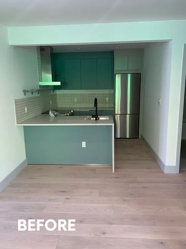 Empty kitchen with teal cabinets and wooden flooring before renovation.