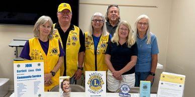 Members of Bartlett Lions Club standing behind a service information table.