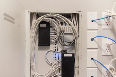 Network wiring and patch panel setup inside a wall cabinet.