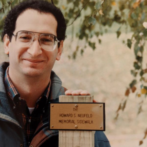 Man standing next to a memorial sidewalk sign.