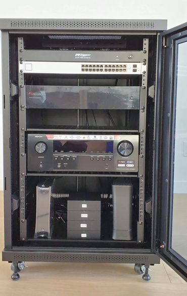 Open black server rack with audio and networking equipment.